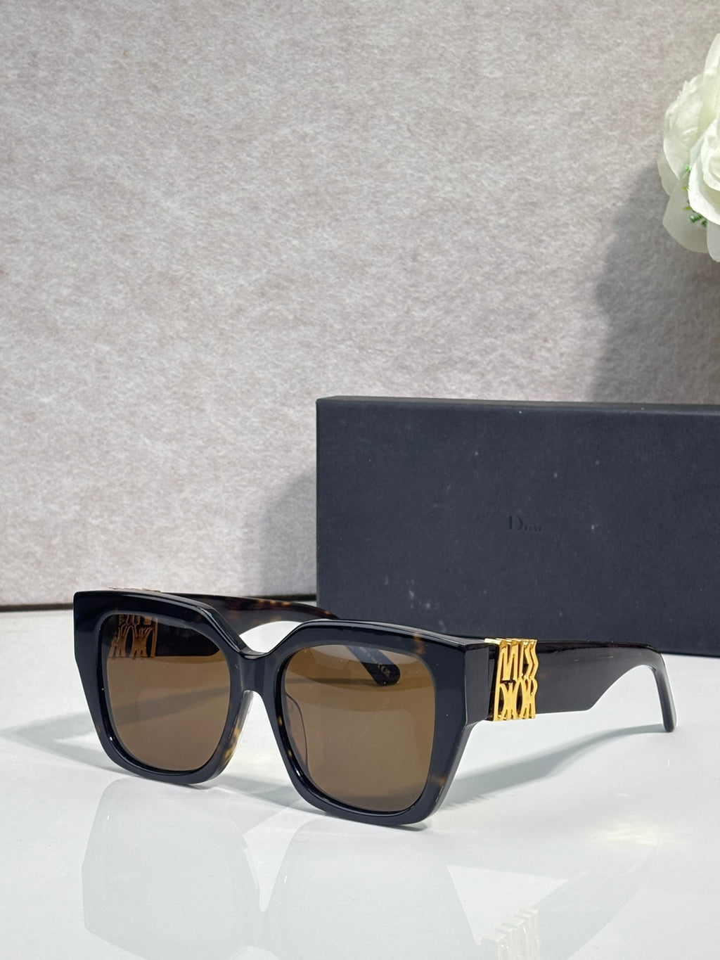 Dior sunglasses with dark frames and brown-tinted lenses, gold logo on temple
