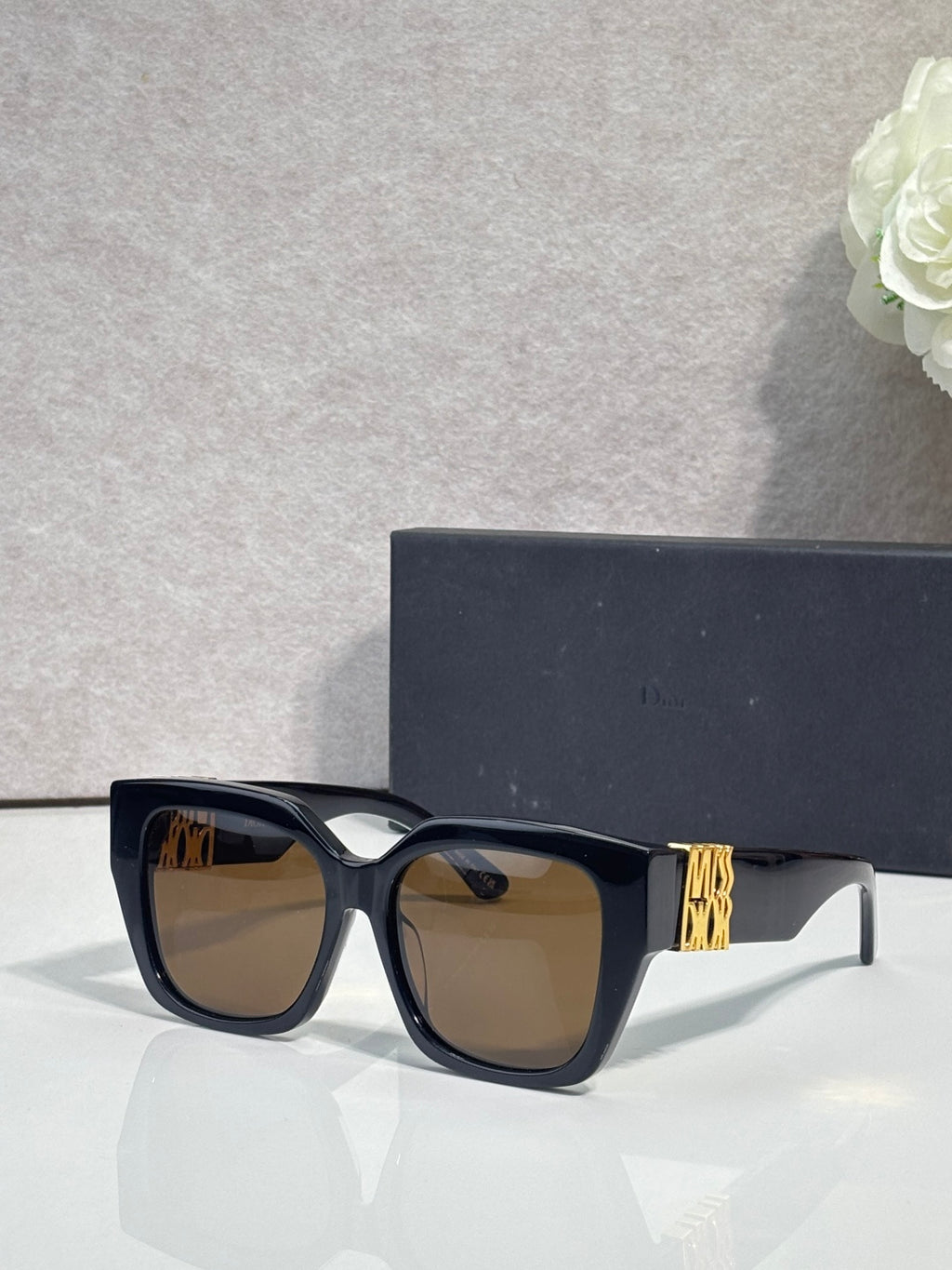 Dior sunglasses with dark frames and brown-tinted lenses, gold logo on temple