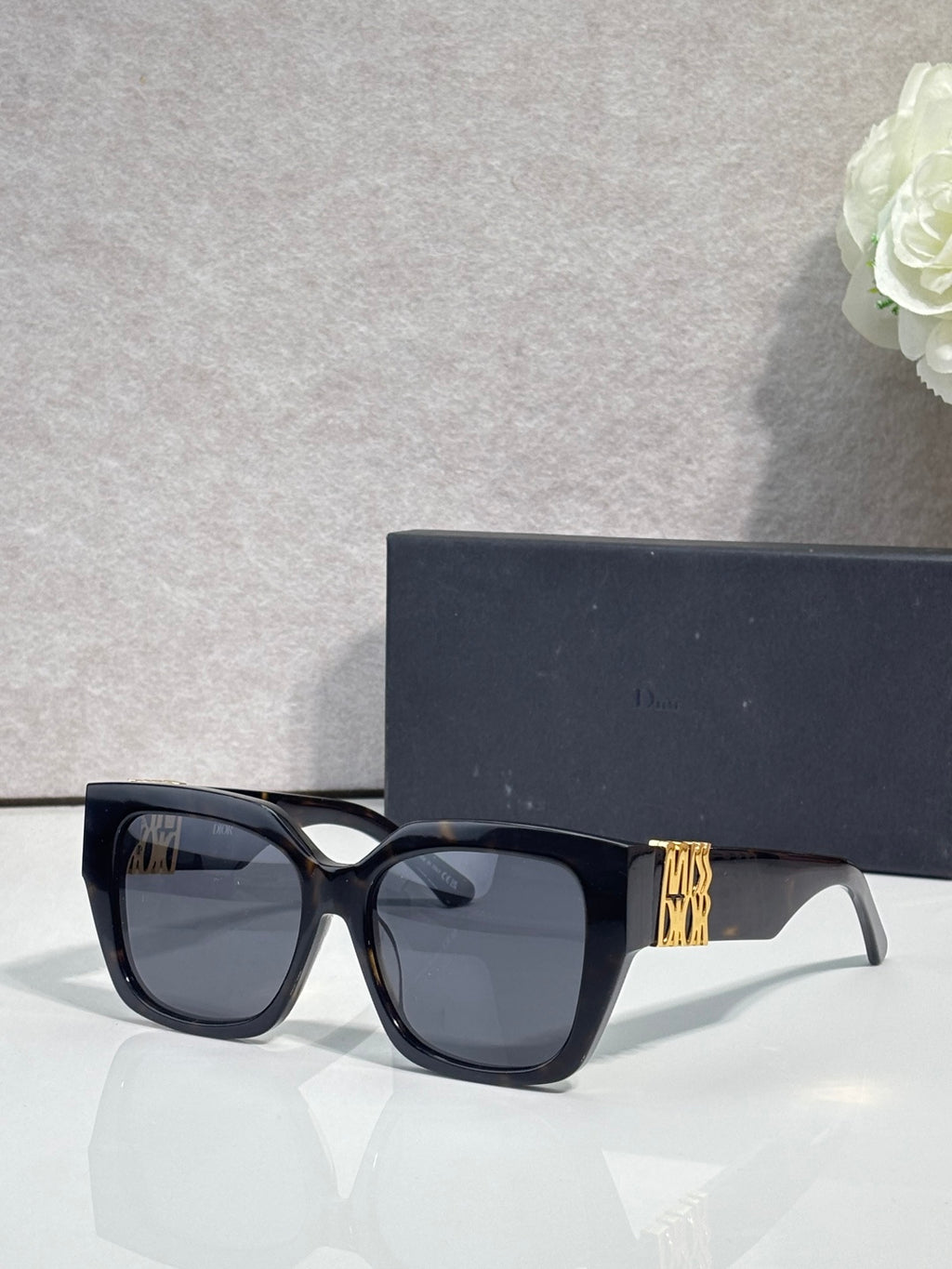 Dior sunglasses with black frames and dark gray lenses, gold logo on temple