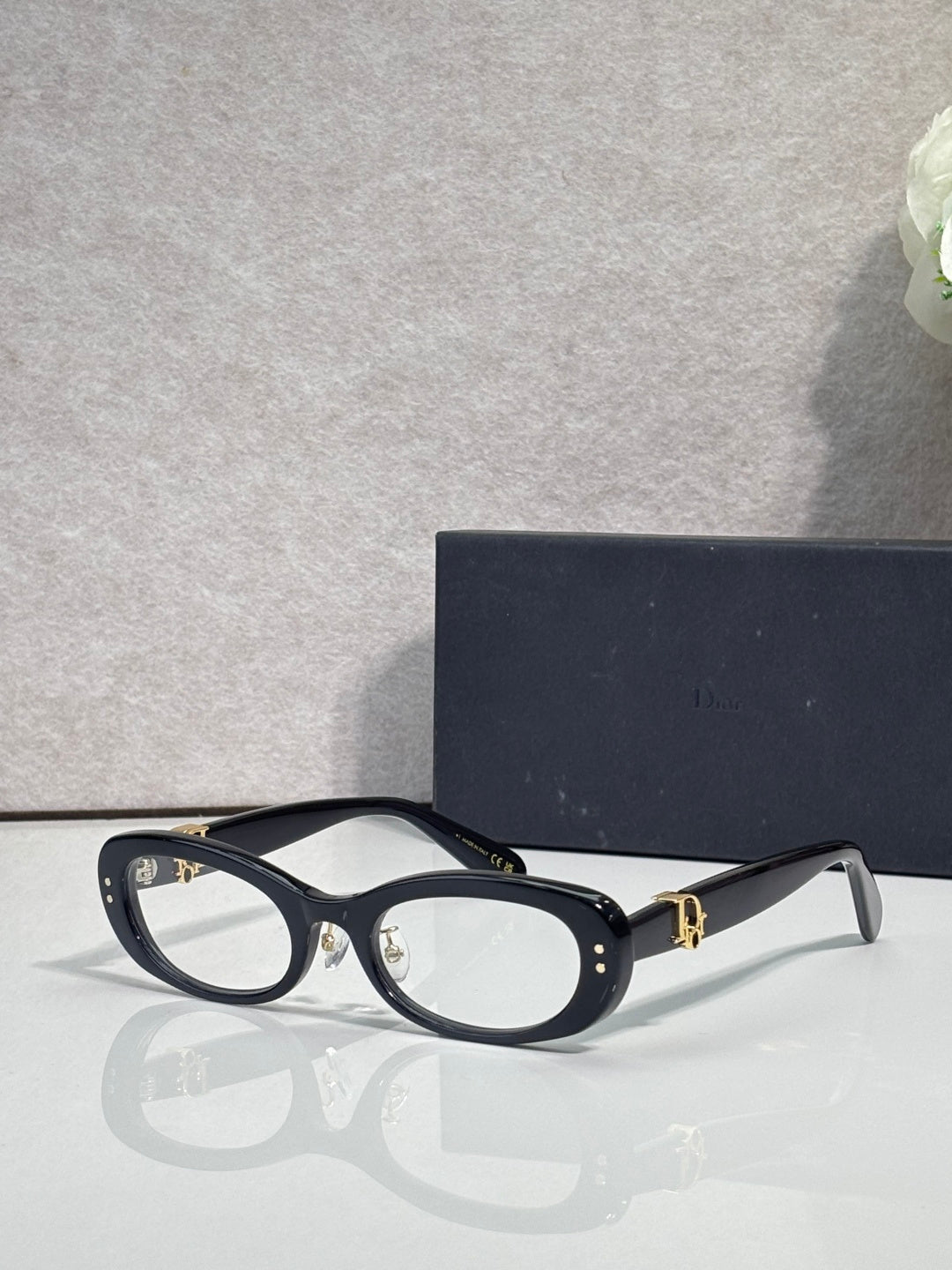 Black oval eyeglasses with clear lenses and gold-tone hinge hardware