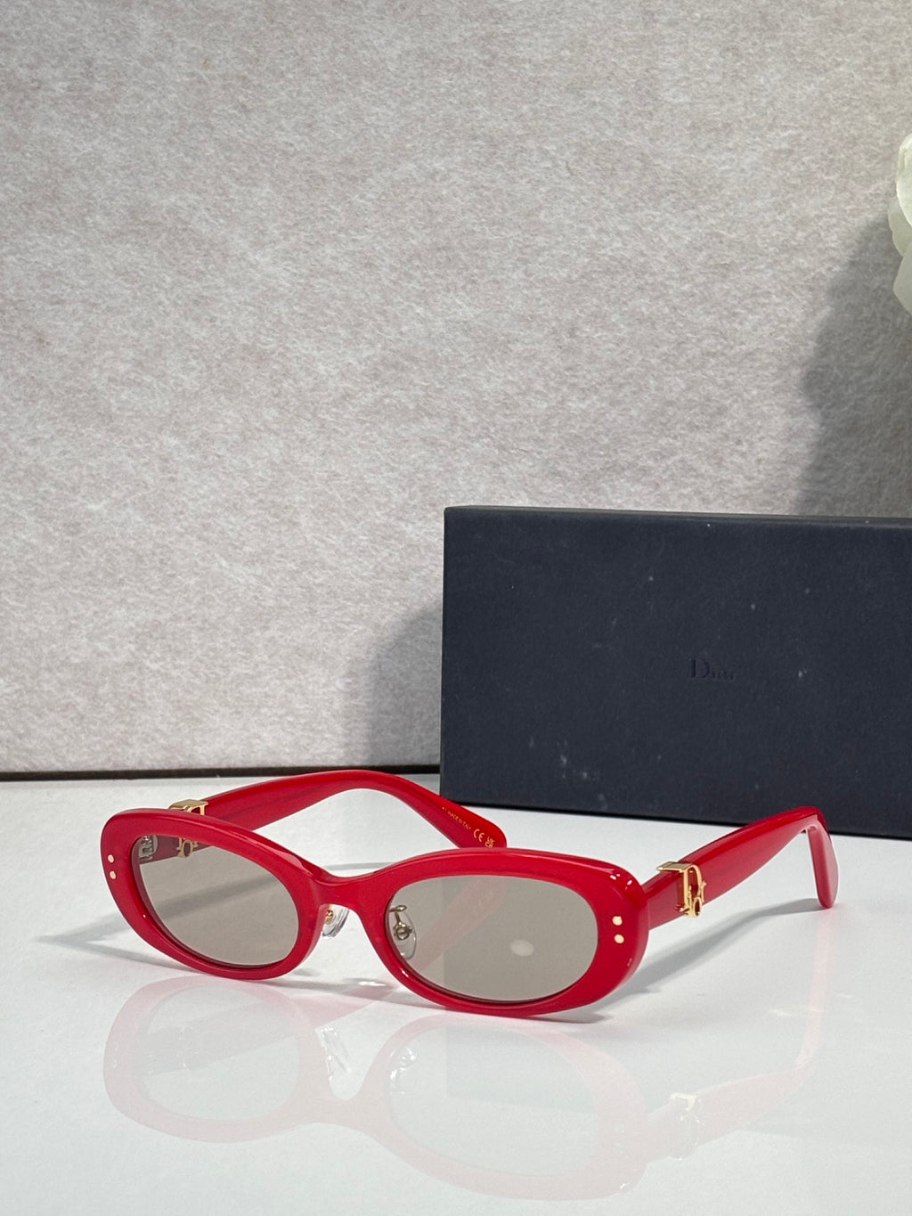 Red oval eyeglasses with clear lenses and gold-tone hinge hardware