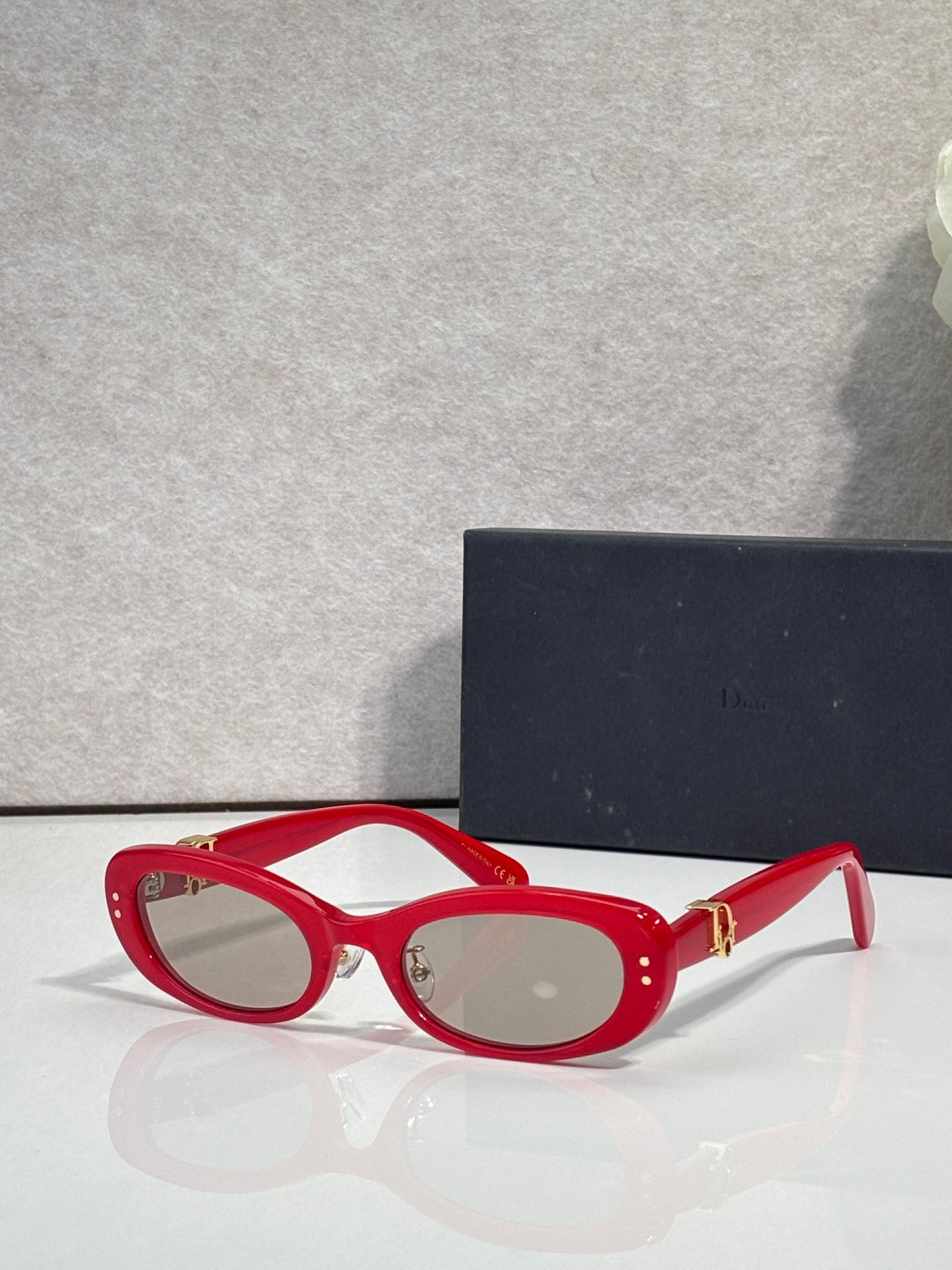 Red oval eyeglasses with clear lenses and gold-tone hinge hardware