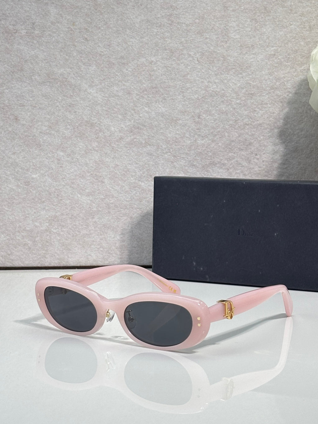 Pink oval eyeglasses with dark lenses and gold-tone hinge hardware
