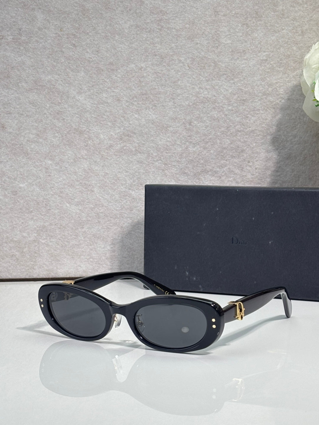 Black oval eyeglasses with dark lenses and gold-tone hinge detail
