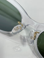Clear frame eyeglasses with green-tinted lenses and visible hinge details