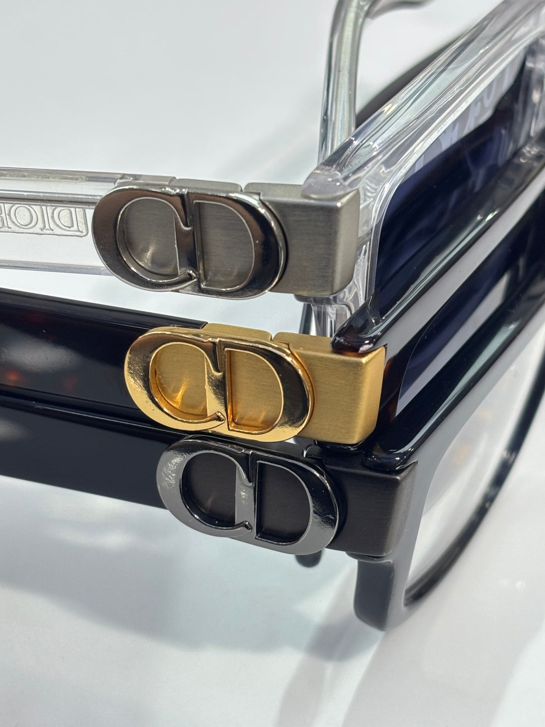 Dior logo hinge on stacked eyeglasses, gold and dark metal frame details