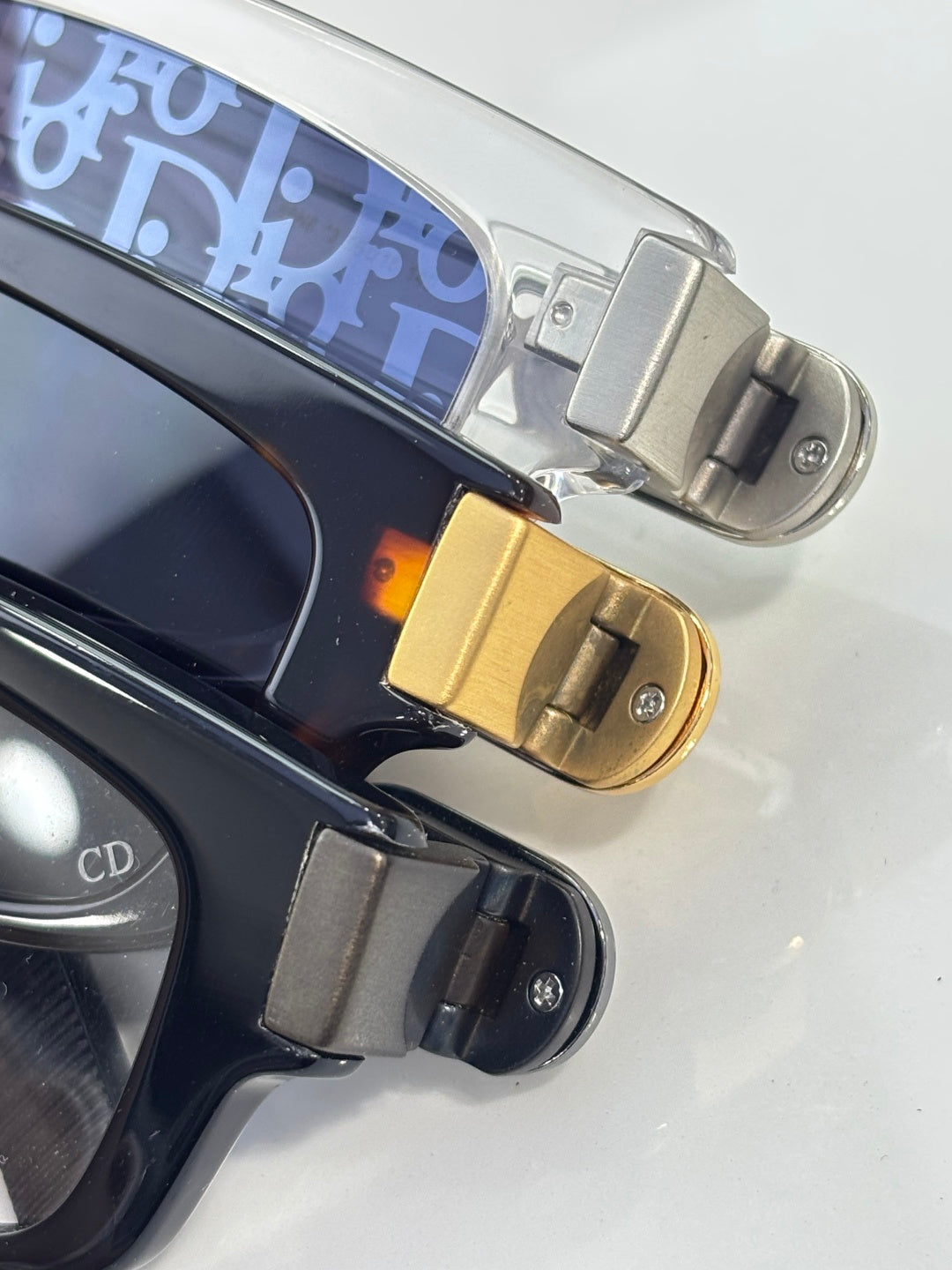 Dior glasses close-up: gold hinge and temple with blue patterned lining.