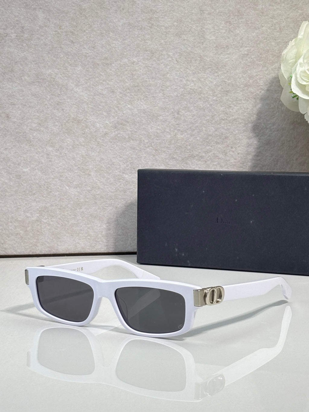 Dior glasses with white frame, dark lenses, and gold logo bridge.