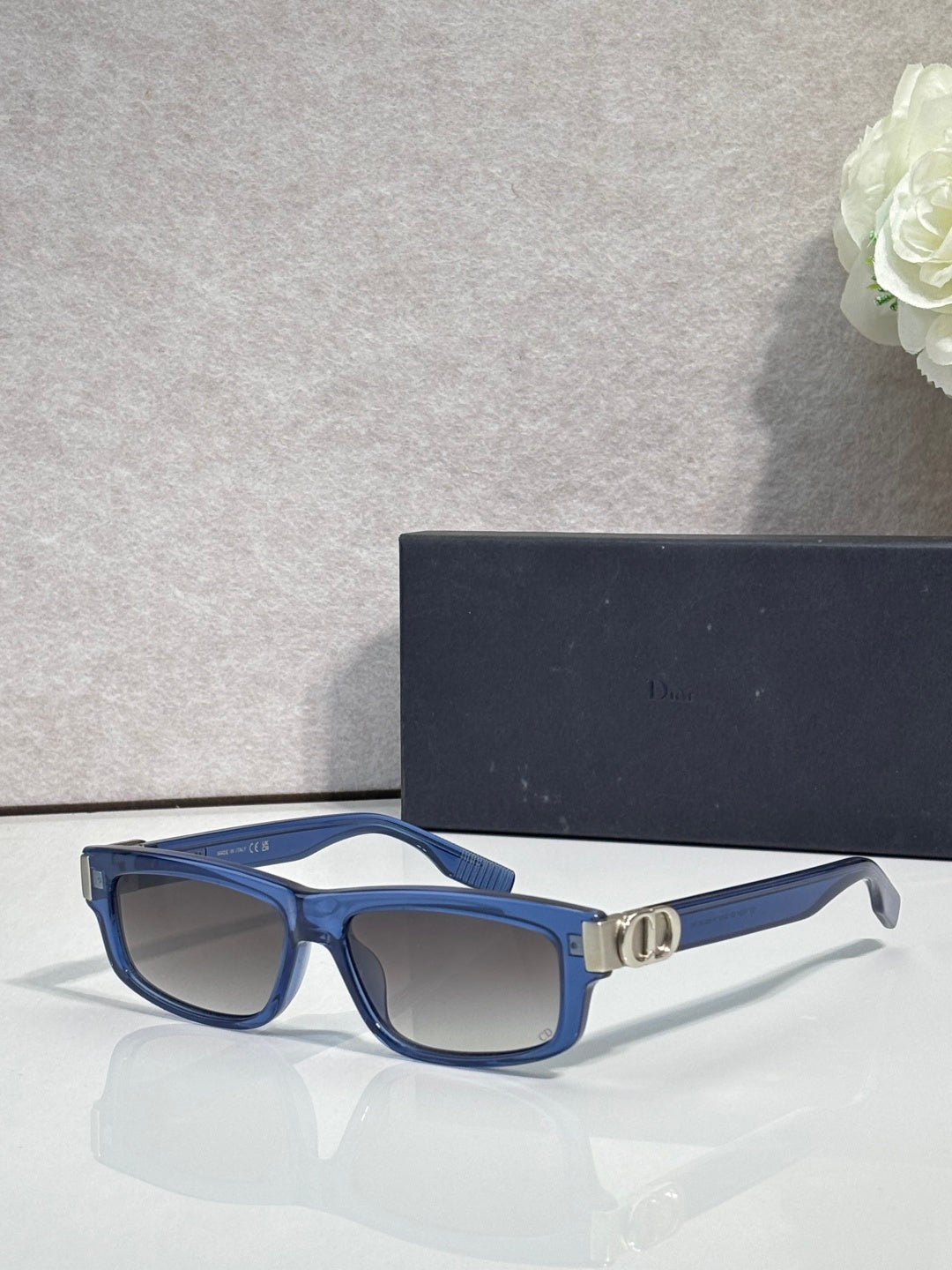 Dior glasses with blue frame, dark lenses, and gold bridge detail.