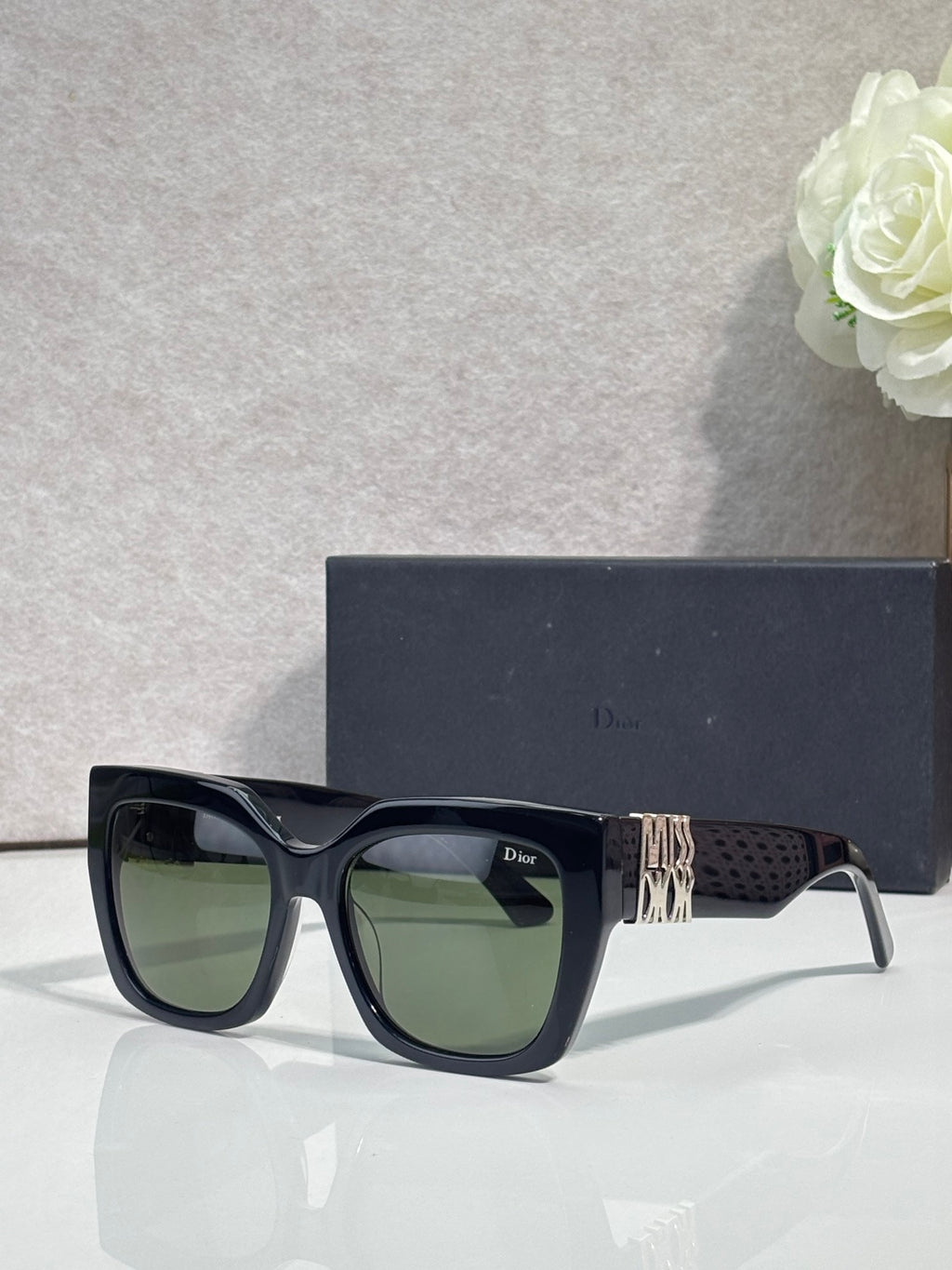 Dior glasses with dark frames, gold temple emblem, and olive-green tinted lenses