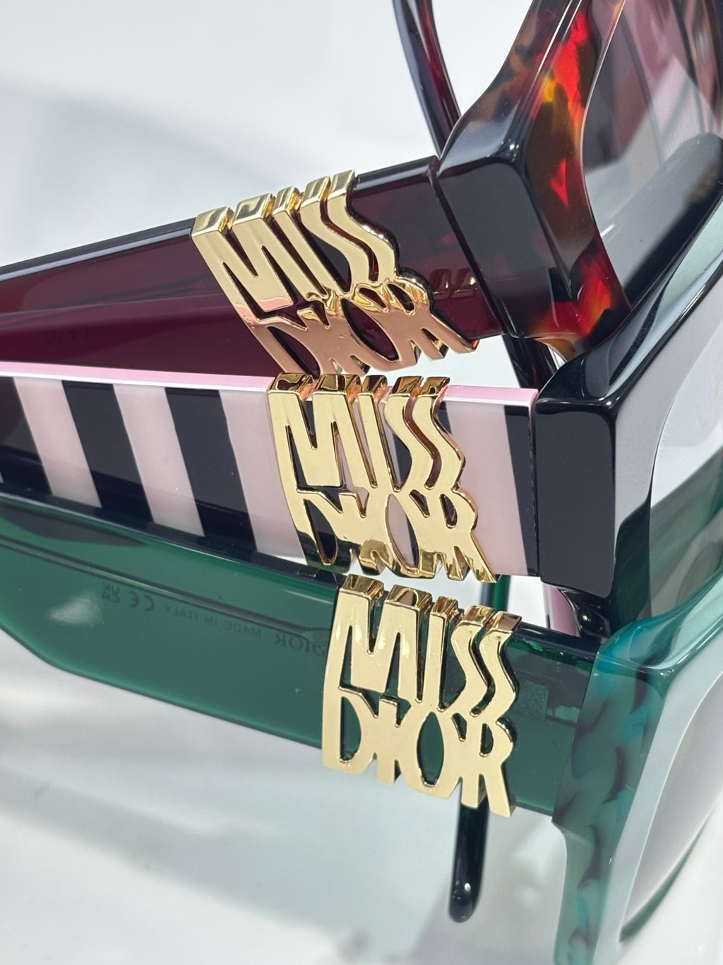 Dior glasses close-up: gold “MISS DIOR” lettering on striped temple