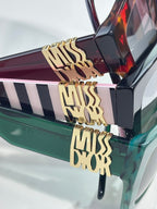 Dior glasses close-up: gold “MISS DIOR” lettering on striped temple