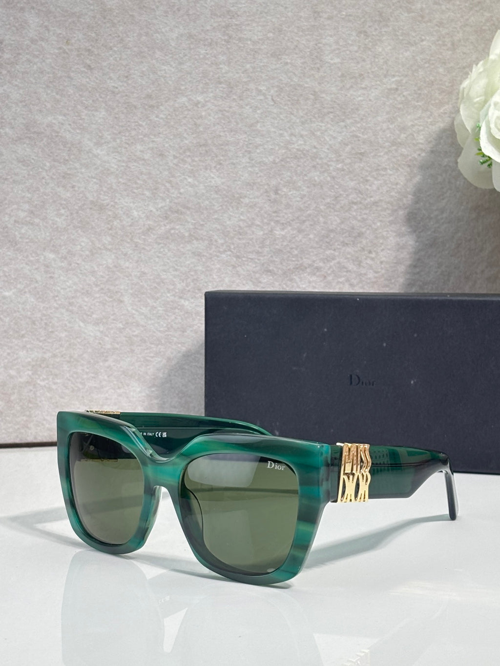 Dior glasses with green frames, gold temple emblem, and tinted lenses