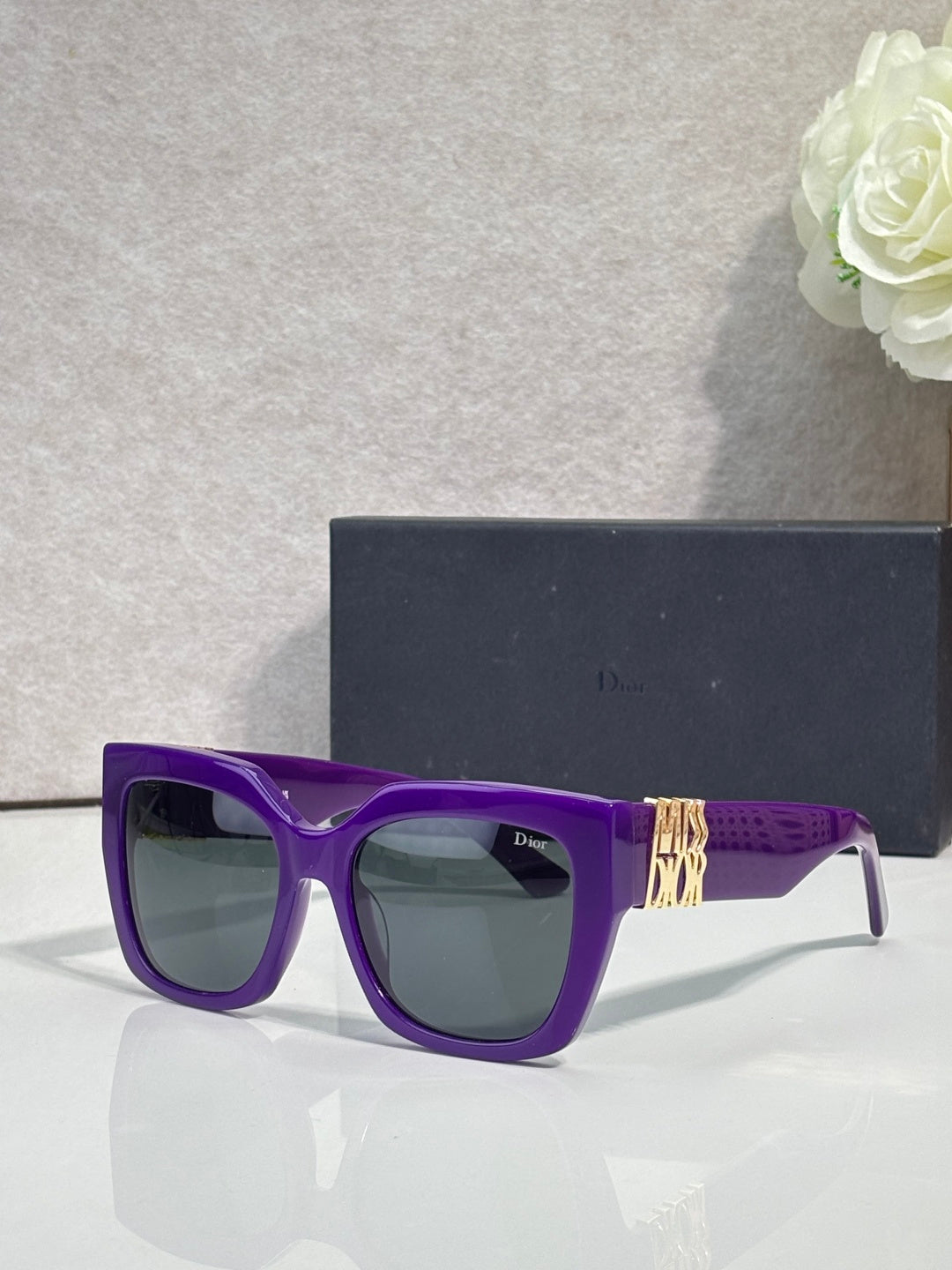 Dior glasses with purple frames, gold temple emblem, and tinted lenses
