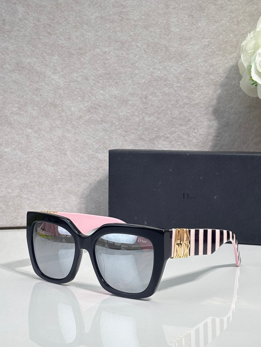 Dior glasses with dark frames, pink-striped temple detail, and clear lenses