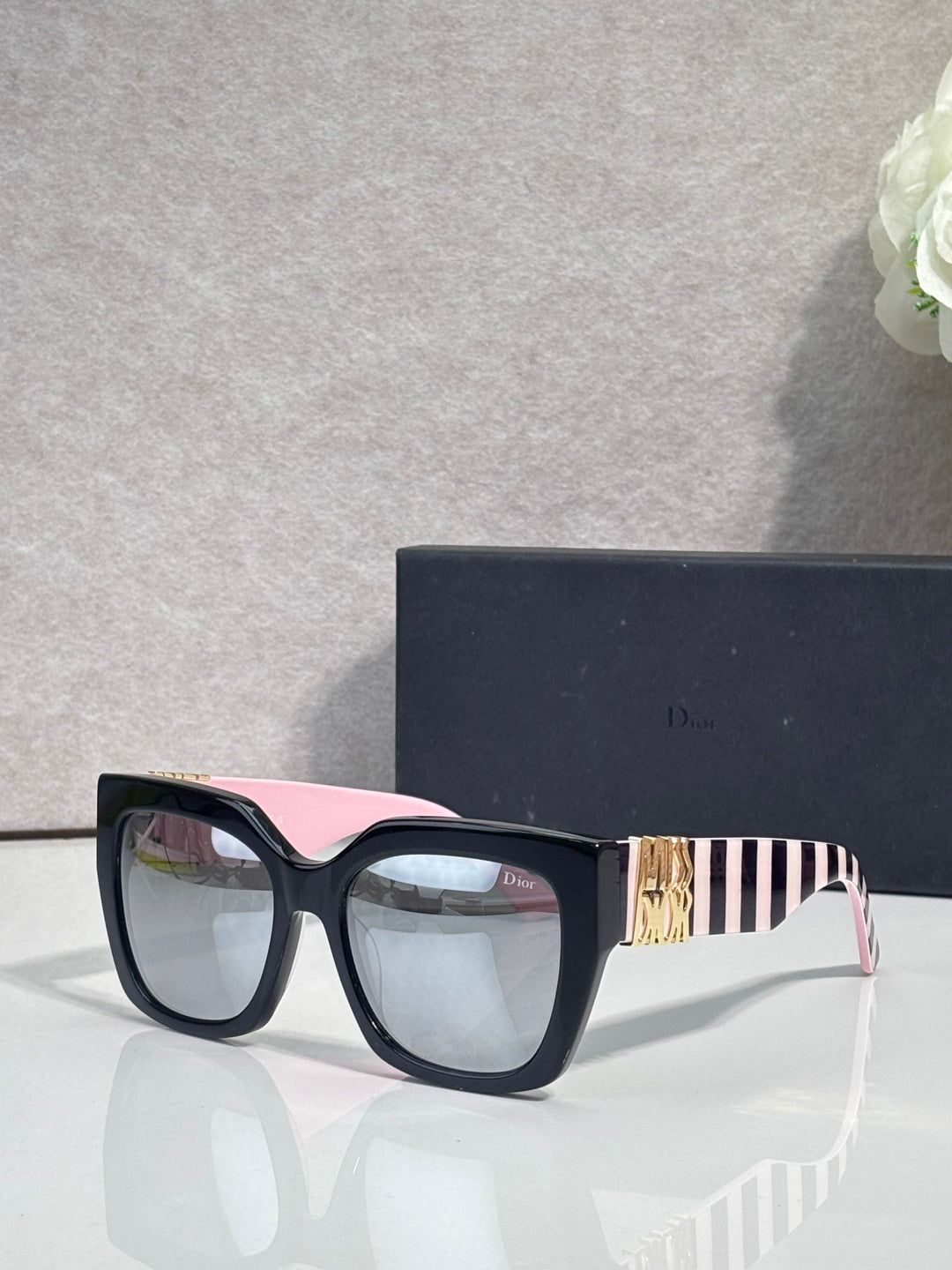 Dior glasses with dark frames, pink-striped temple detail, and clear lenses
