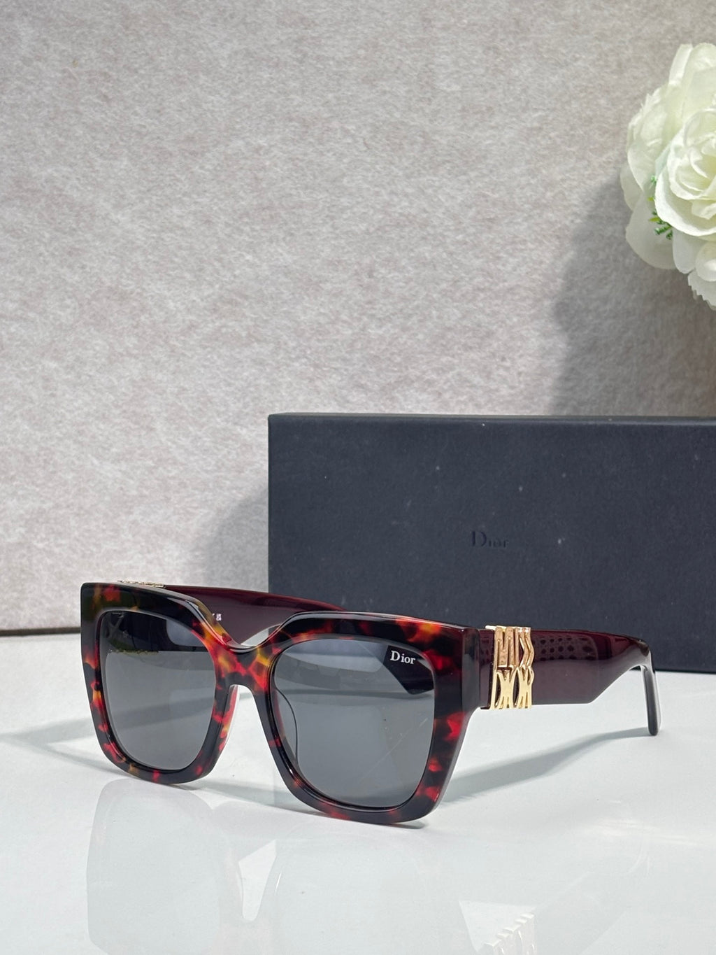 Dior glasses with tortoiseshell frames, gold temple emblem, and dark lenses