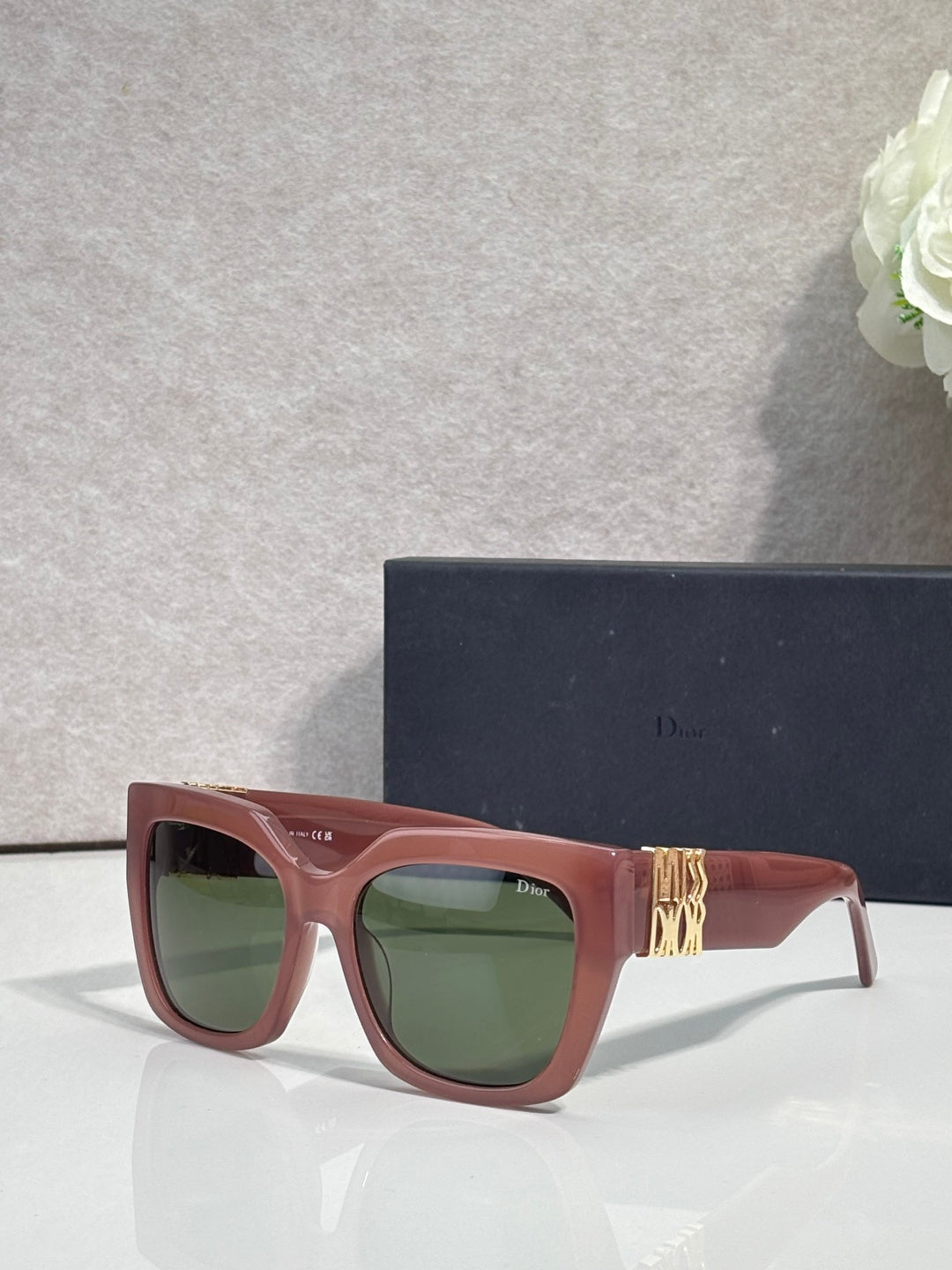 Dior glasses with burgundy frames, gold emblem on temple, and green lenses