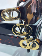 Sunglasses close-up: gold LV emblems on dark frame with tortoiseshell accents