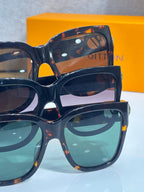 Sunglasses stack with dark tortoiseshell frames, tinted lenses, and gold logo details
