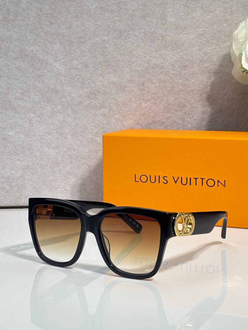 Sunglasses with dark tortoiseshell frame, tan-tinted lenses, and gold LV emblem on temple