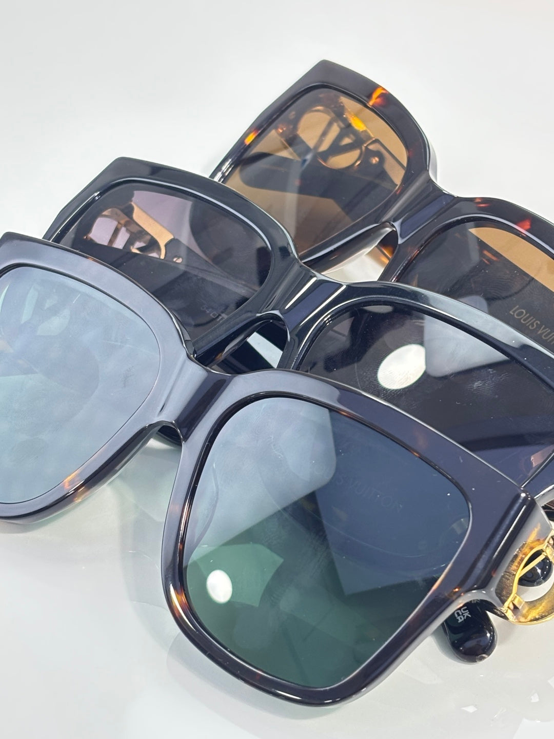 Sunglasses set with blue-tinted lenses, dark frames, and gold logo accents on temples