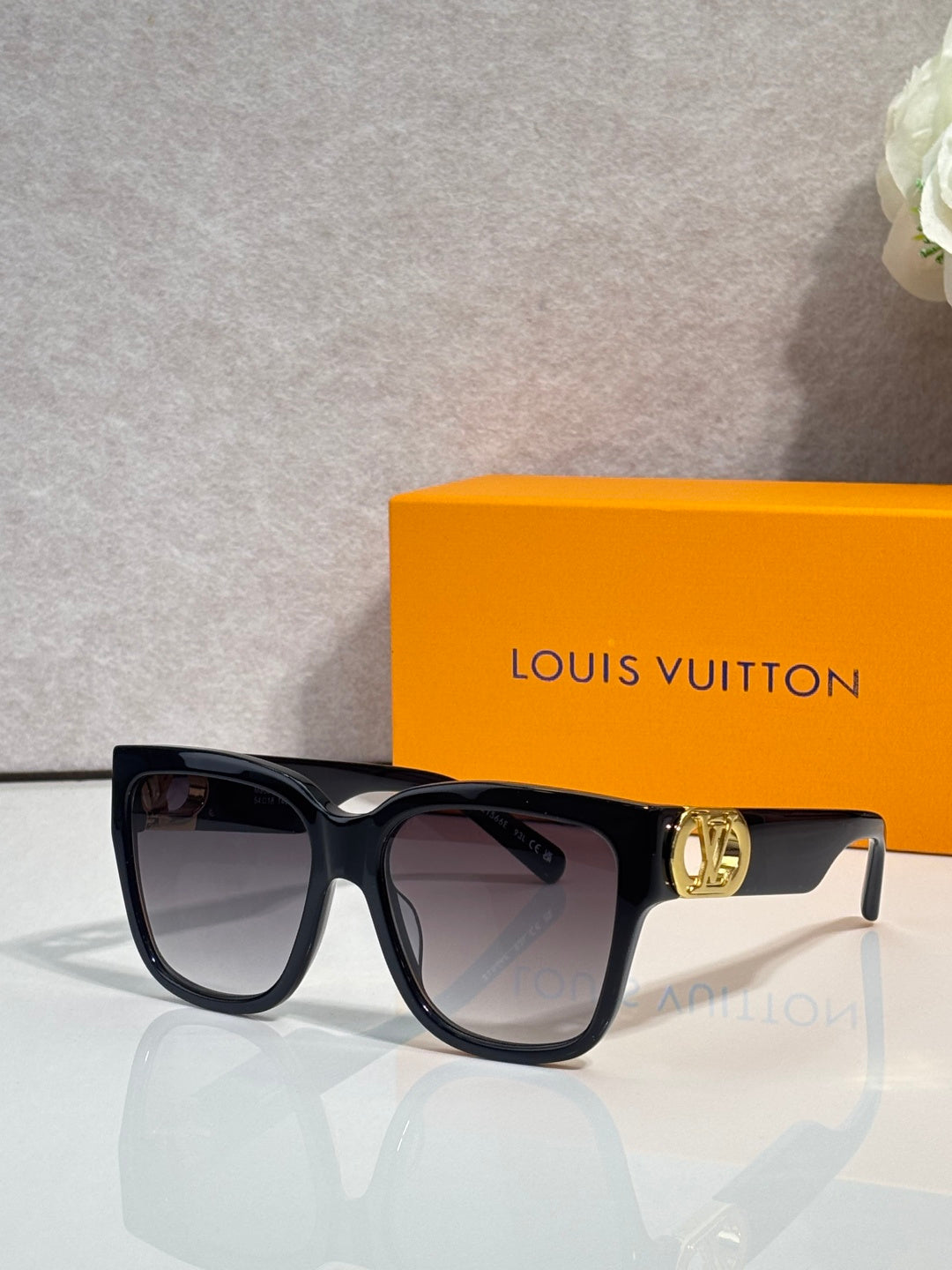 Sunglasses with dark frame and smoky lenses, featuring a gold LV emblem on the side