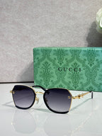 Gucci glasses with dark blue tinted lenses, black frame with gold accents and temples