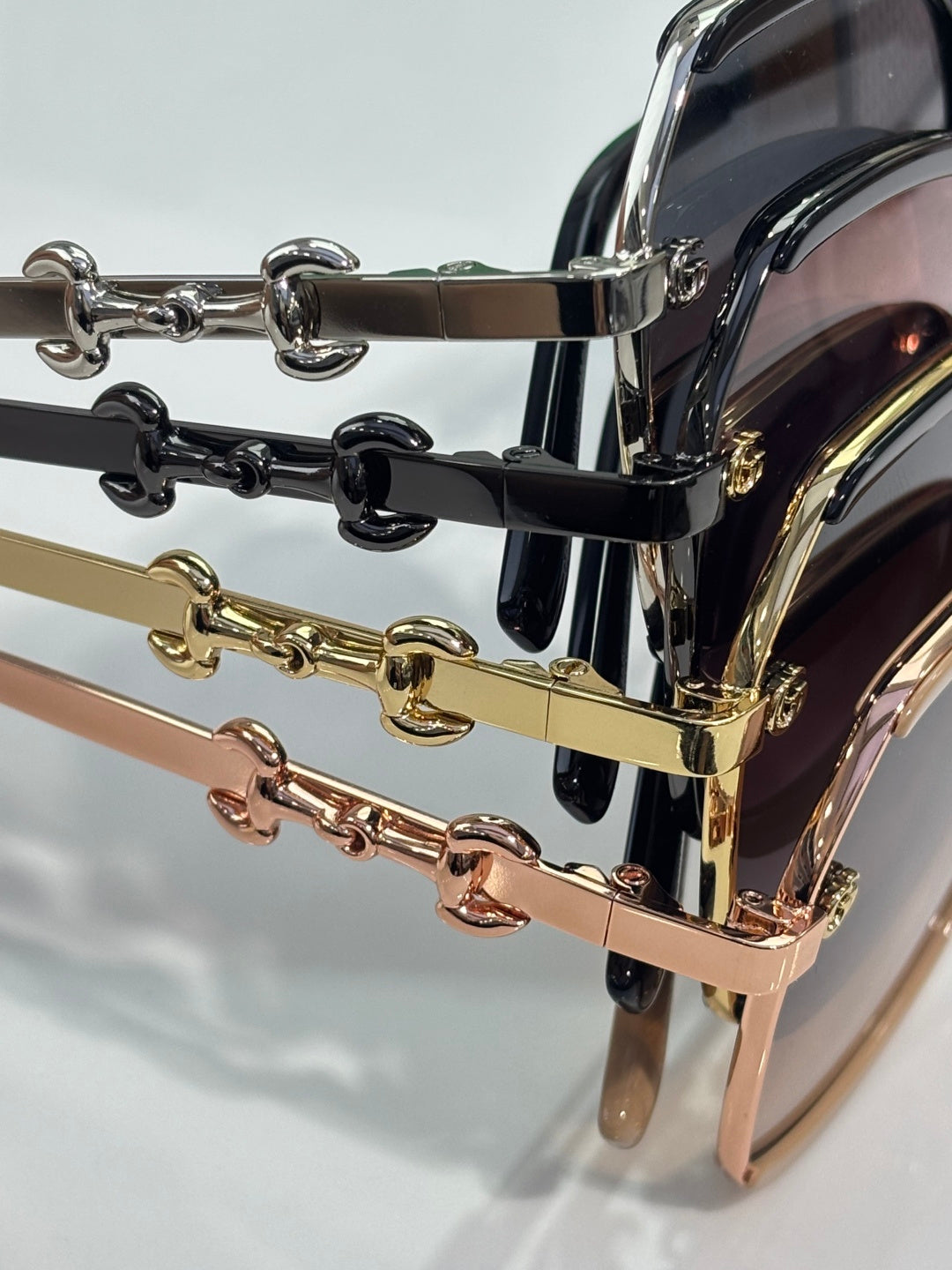 Gucci glasses close-up: gold, pink, and black chain-link temple details with metal bars