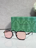 Gucci glasses with pink tinted lenses, black frame with gold hinges and chain detail