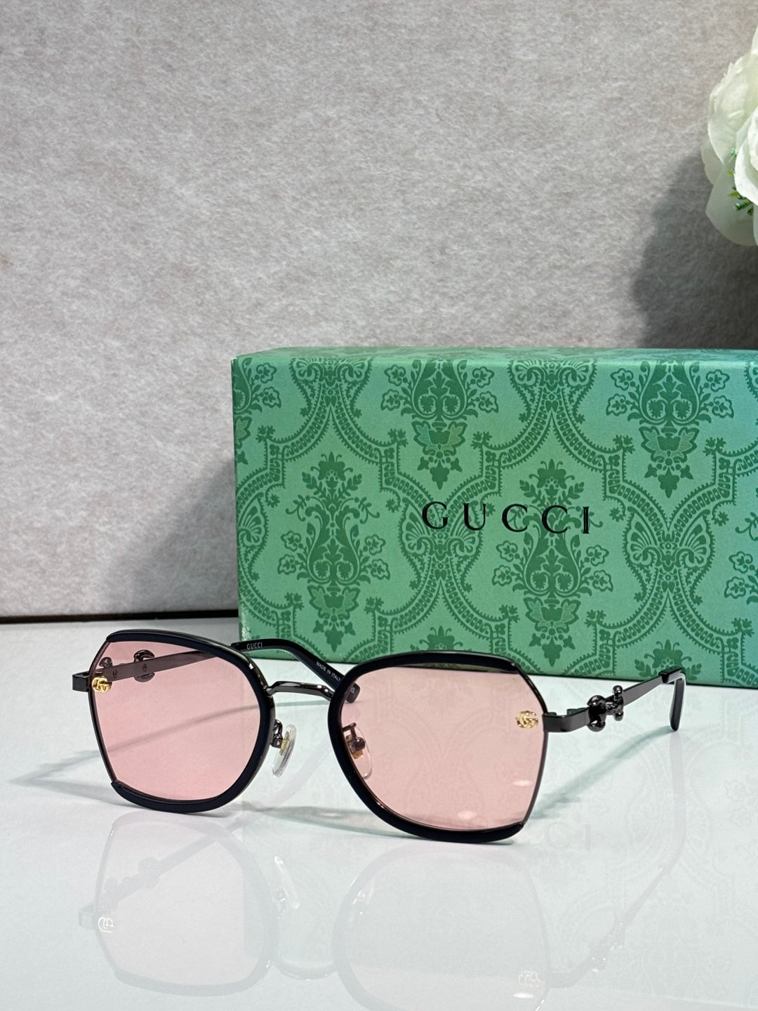 Gucci glasses with pink tinted lenses, black frame with gold hinges and chain detail