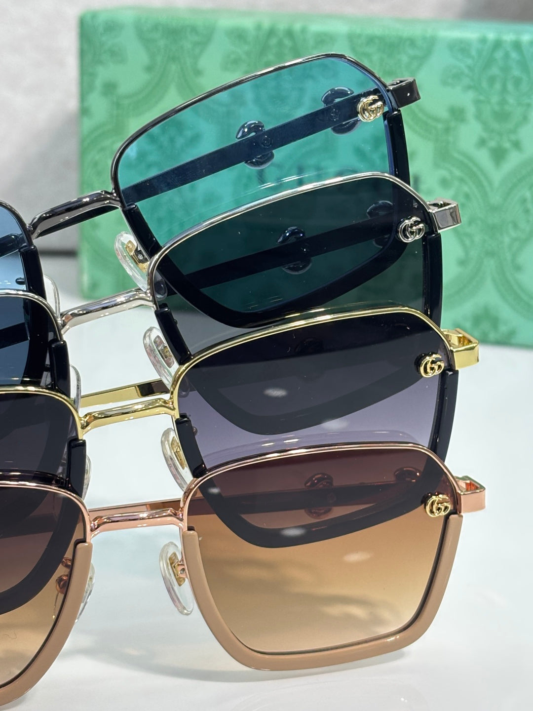 Gucci sunglasses pair with stacked lens tones in blue, dark, and beige, gold frames