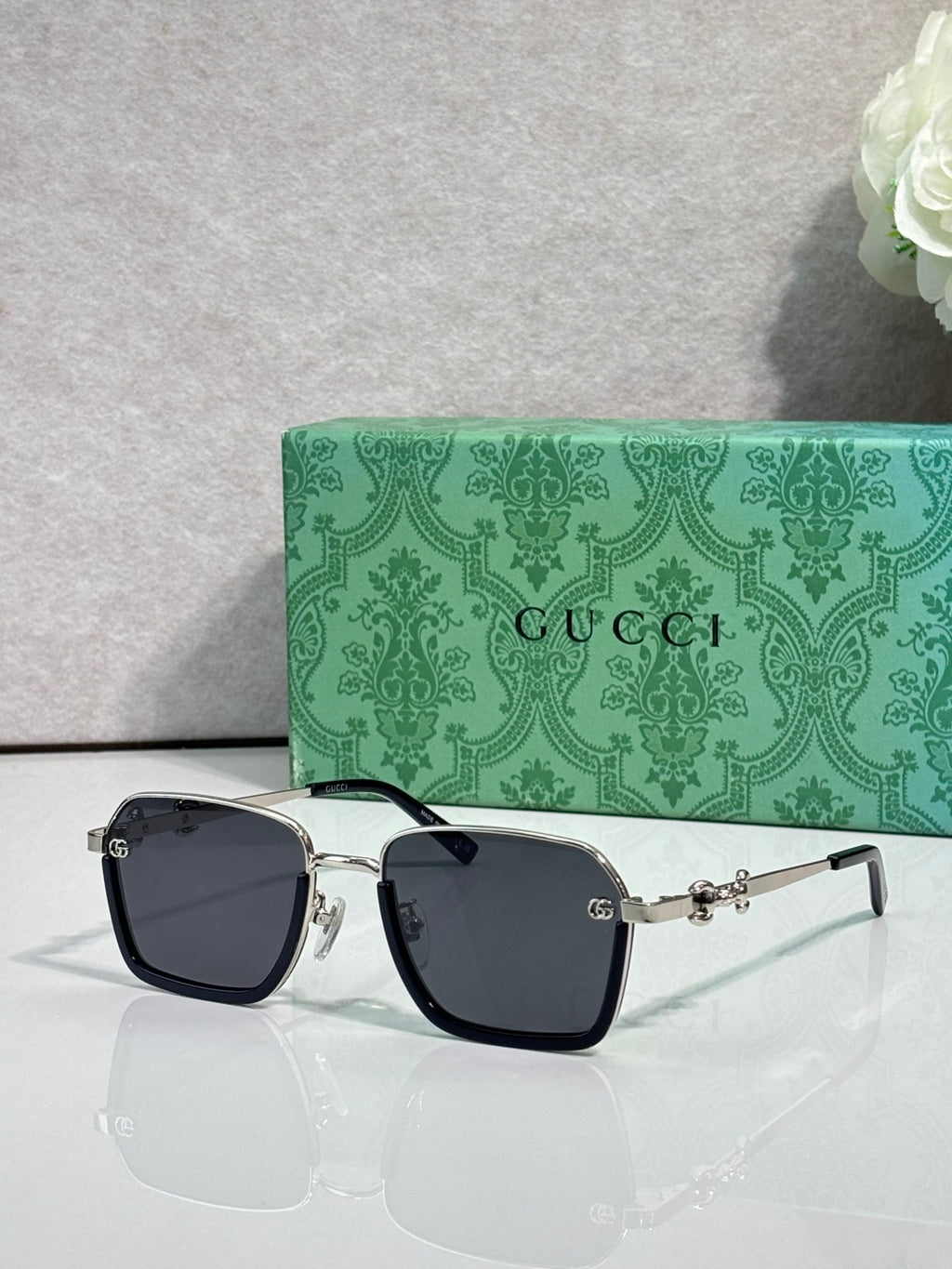 Gucci sunglasses with black frames and dark lenses, gold and silver side details