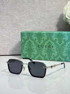 Gucci sunglasses with black frames and dark lenses, gold and silver side details