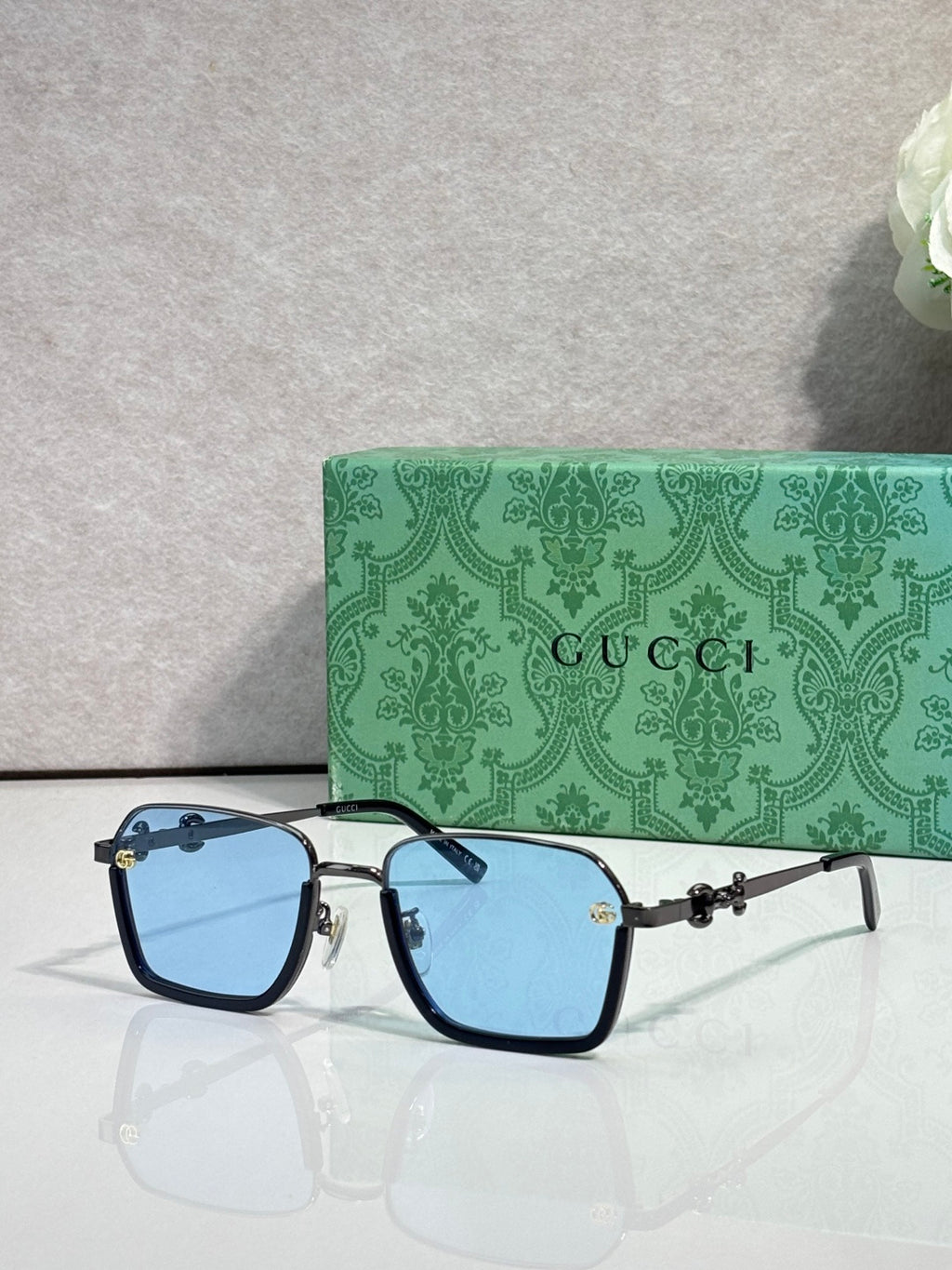 Gucci sunglasses with black frames and light blue gradient lenses, gold accents