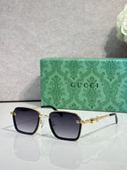 Gucci sunglasses with black frames, dark lenses, and gold bridge hardware
