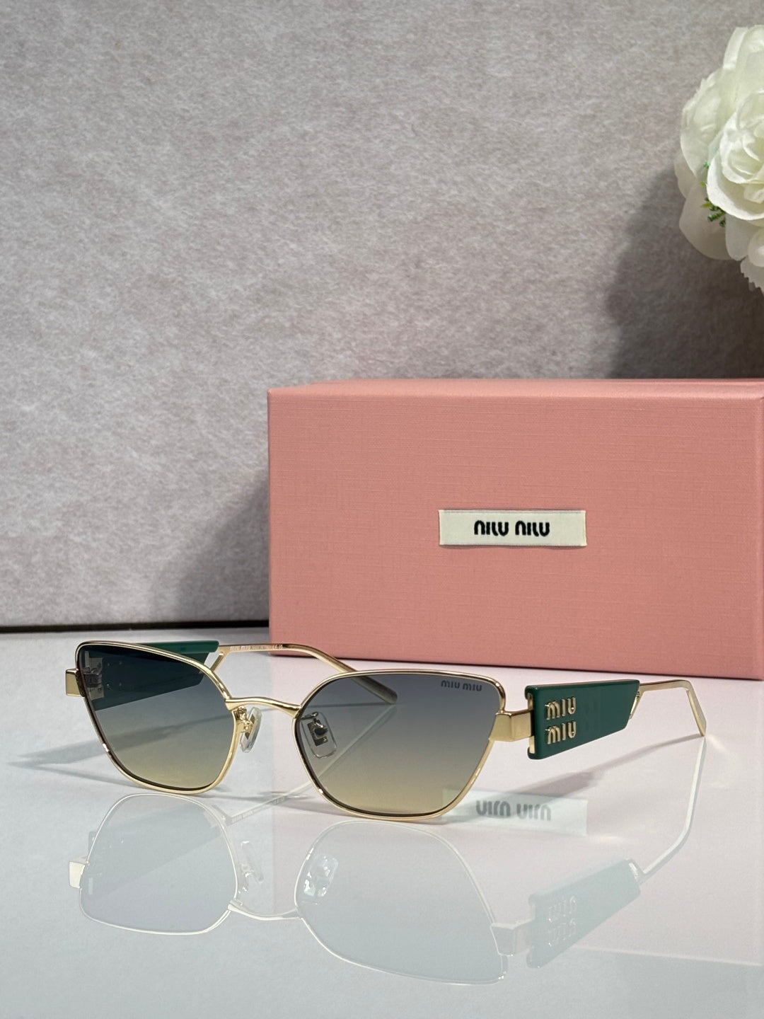 MiuMiu sunglasses with gold frame and dark green lenses