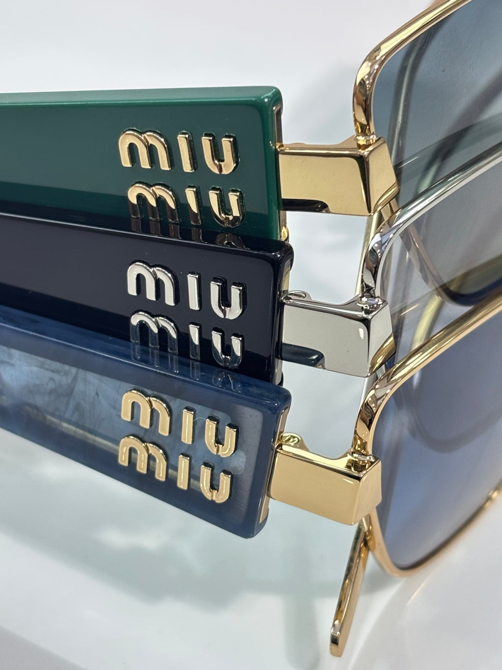 MiuMiu sunglasses temples with stacked logo plates and gold accents