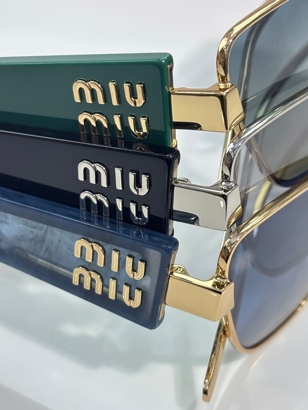 MiuMiu sunglasses temples with stacked logo plates and gold accents