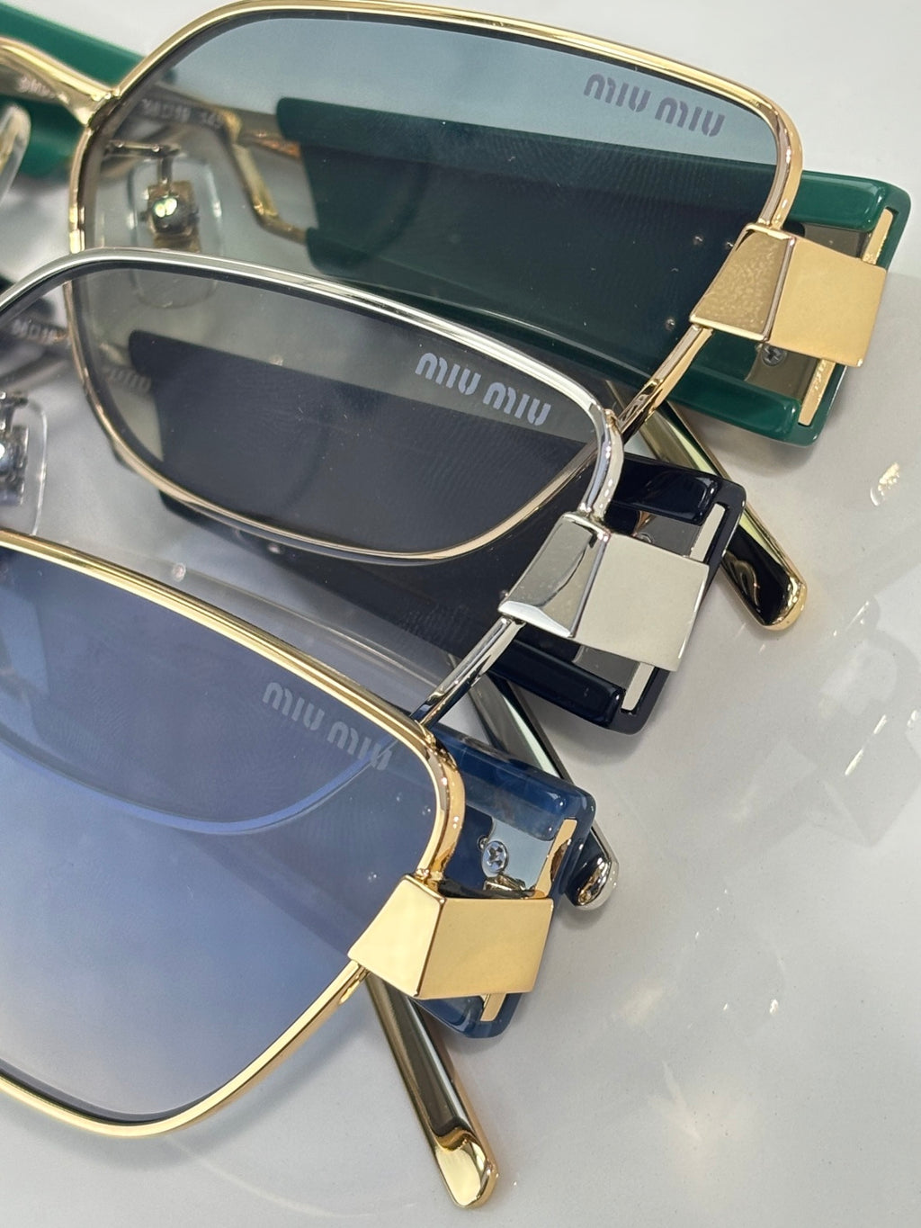 MiuMiu sunglasses close-up with gold frame and navy lenses