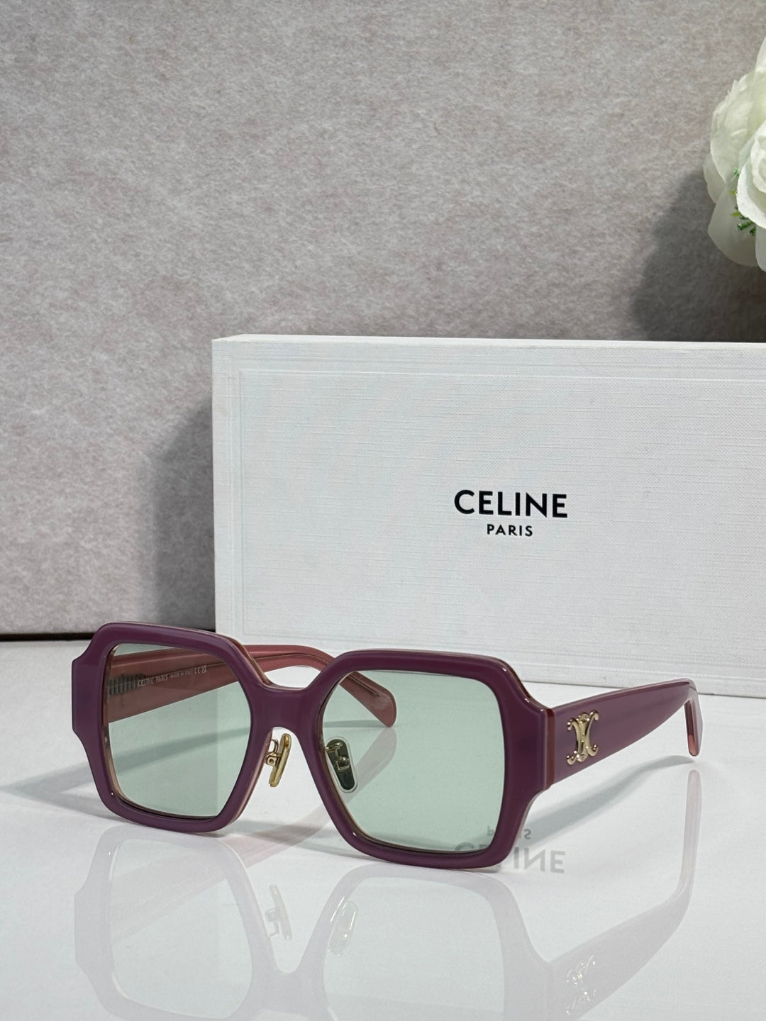 Maroon rectangular sunglasses with light green-tinted lenses and gold logo on the temple