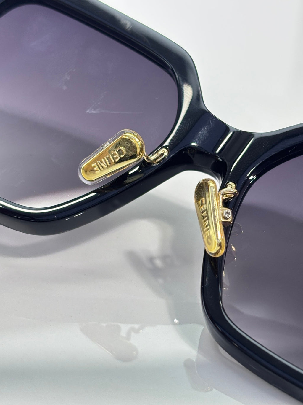Close-up of navy sunglasses frame with gold logo plaque on the temple