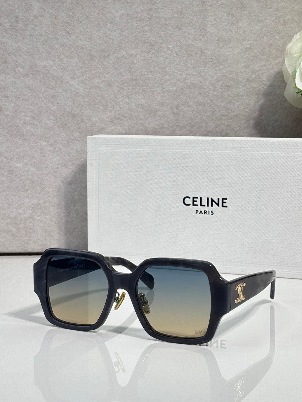 Black rectangular sunglasses with gradient lenses and gold logo detail on the temple