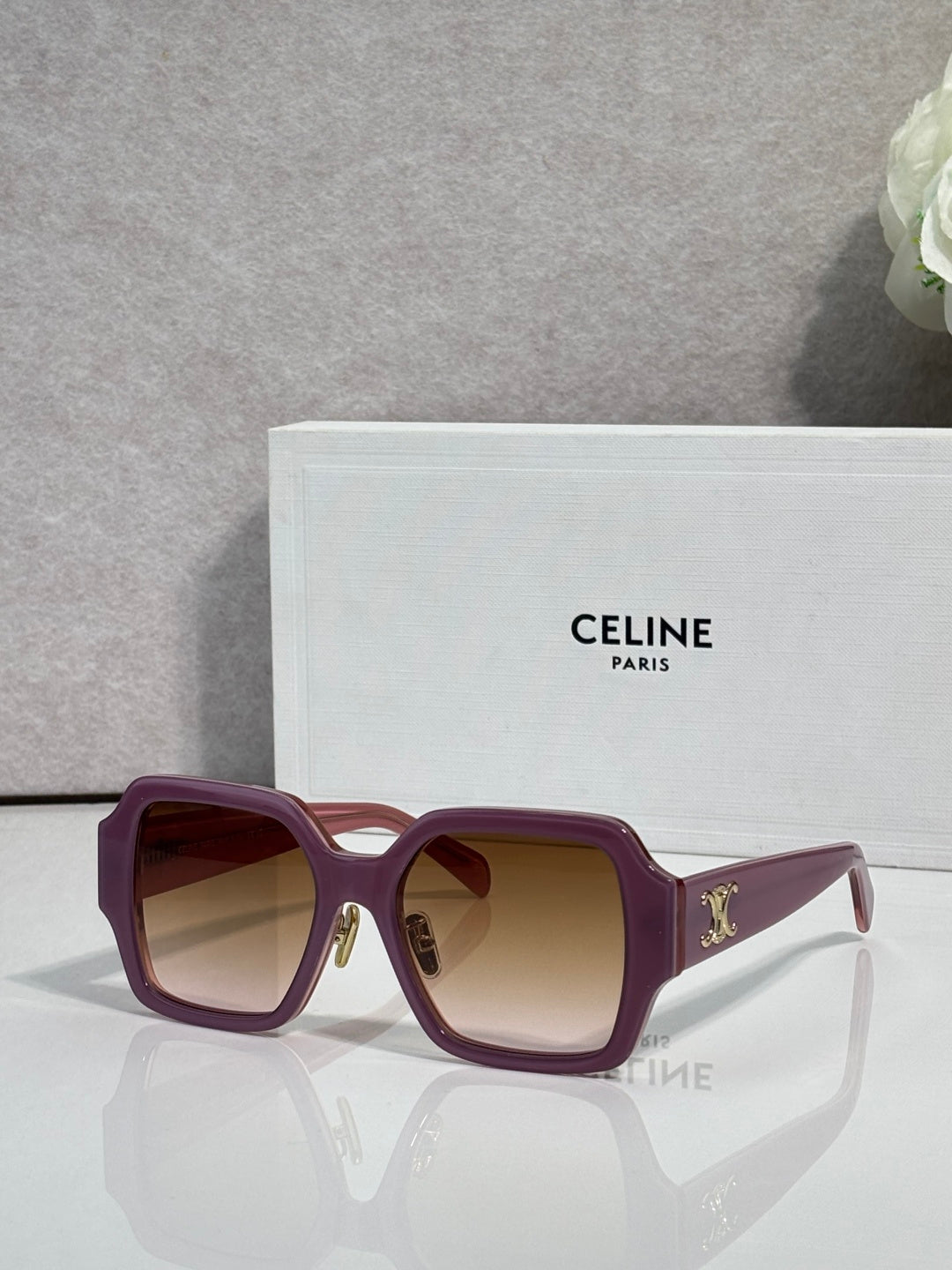 Burgundy rectangular sunglasses with gradient lenses and gold logo on the temple