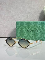Gucci sunglasses with dark lenses and gold metal frames, maroon side accents