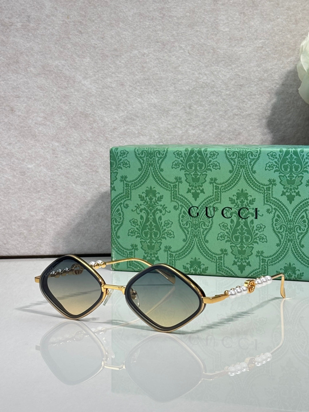 Gucci sunglasses with dark lenses and gold metal frames, maroon side accents