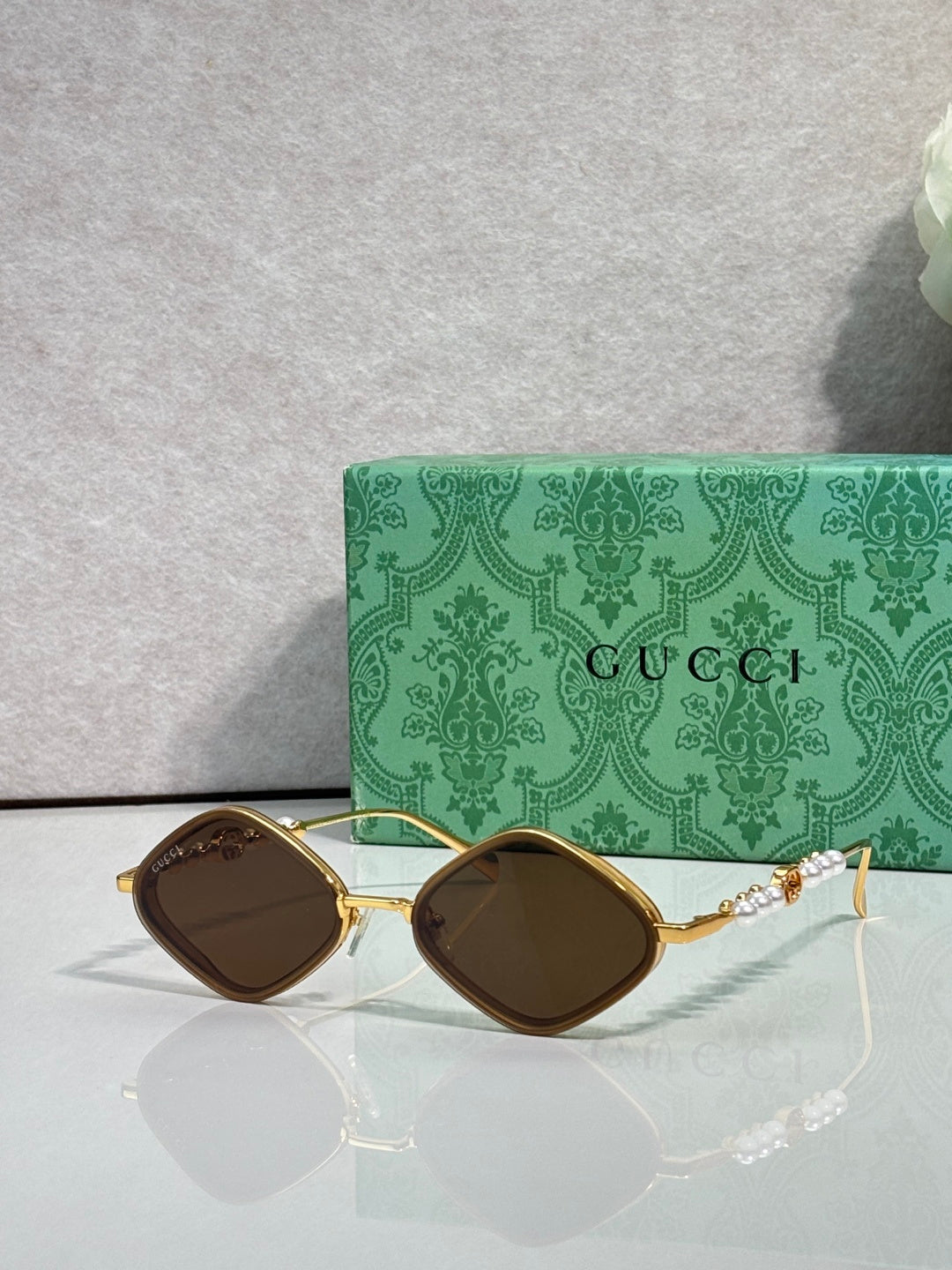 Gucci sunglasses with dark brown lenses and gold metal frames, arched square style