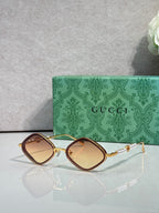 Gucci sunglasses with amber-brown lenses and gold metal frames, arched square style