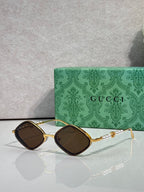 Gucci sunglasses with dark brown lenses and gold frames, black front accents