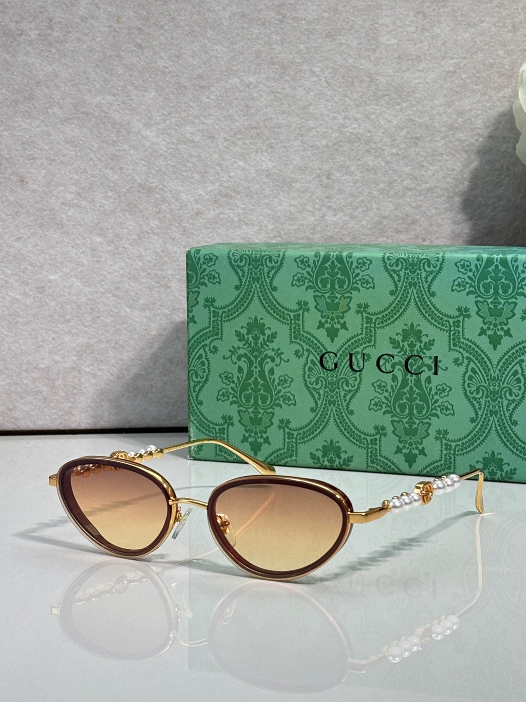 Gold oval sunglasses with warm brown gradient lenses and ornate chain-link arms